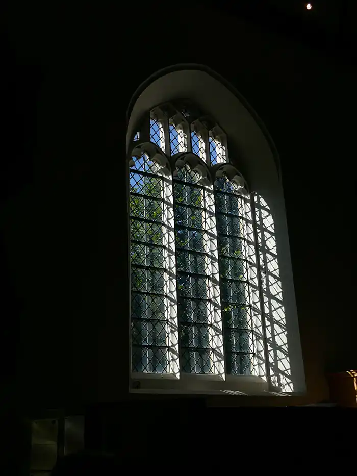 Sunlight streaming through a tall church window into a dark interior