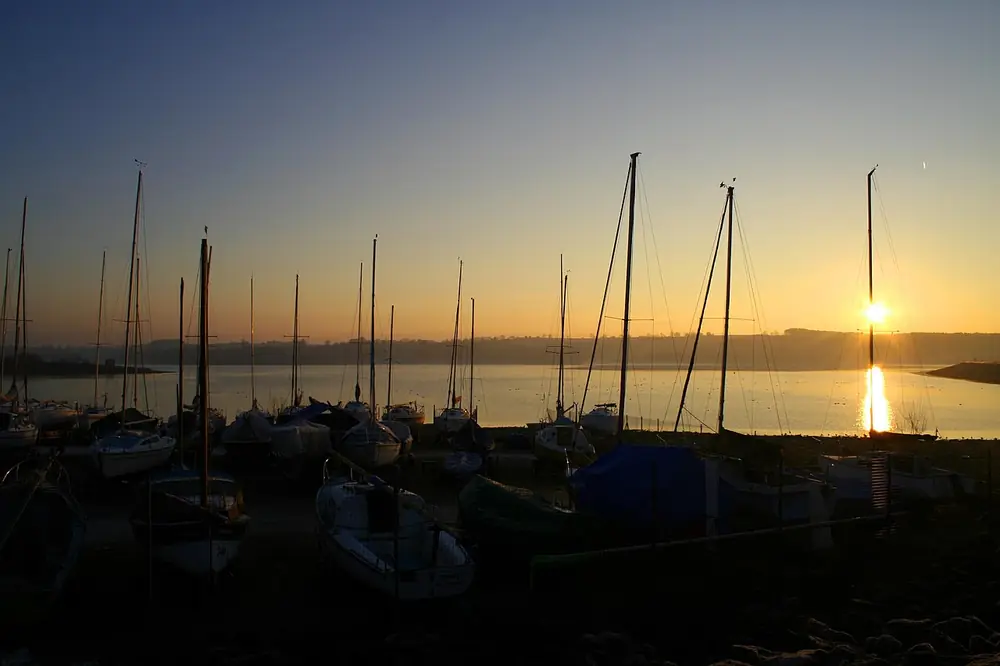 Sunrise over a marina with sailboat masts silhouetted against the sky
